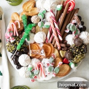 A Christmas dessert charcuterie board on a marble platter with green glasses.