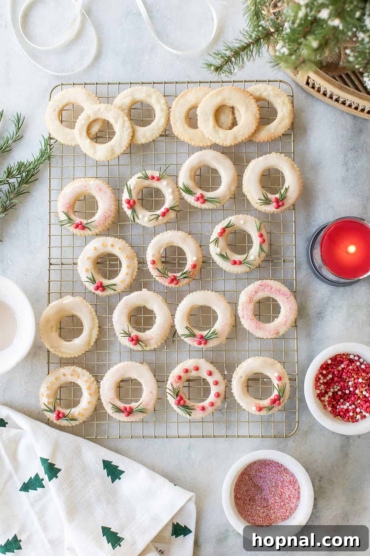 Rows of baked but unglazed wreath-shaped Christmas cookies cooling on a wire rack, ready for decoration.