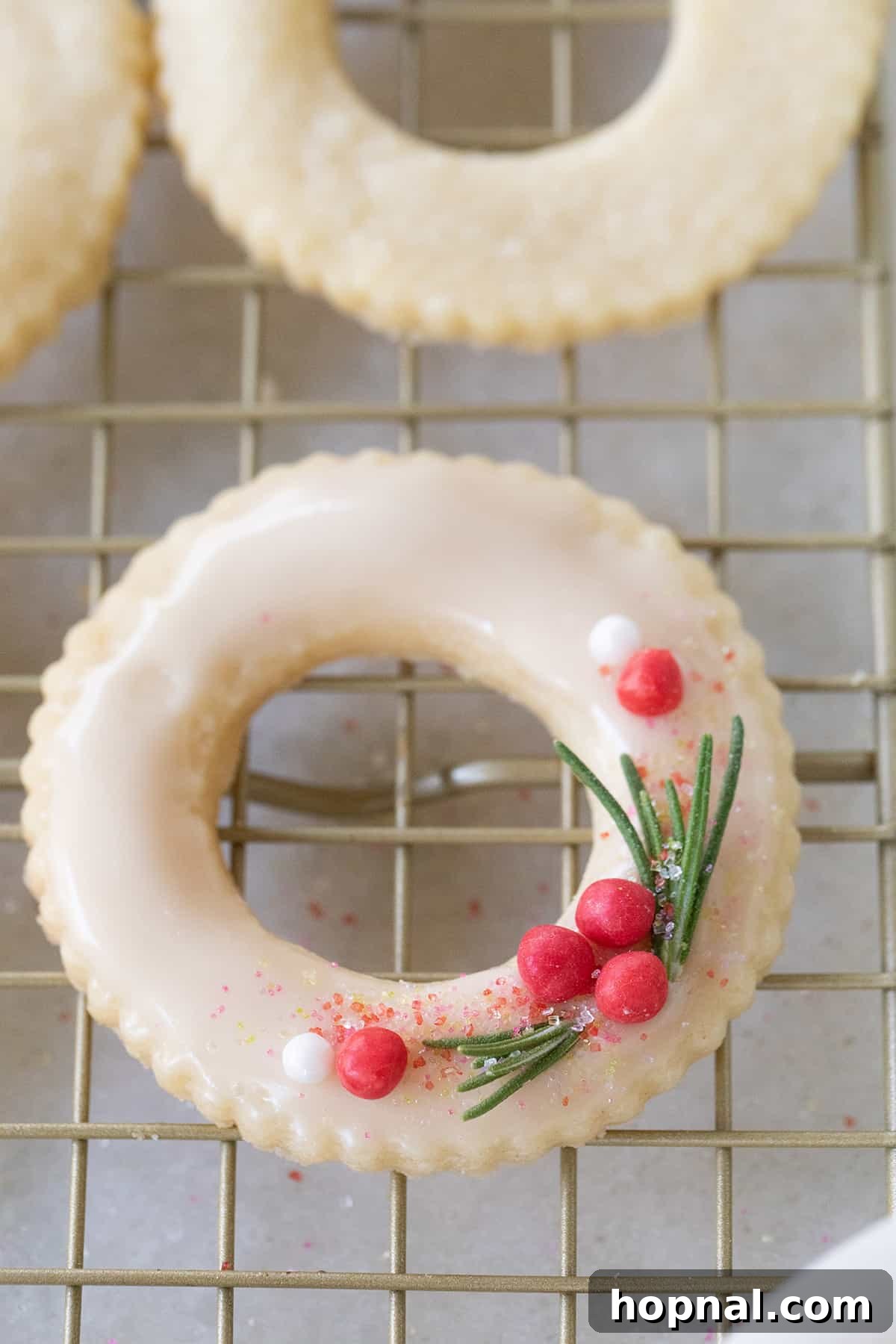 A single perfectly baked Christmas wreath cookie, without glaze, cooling on a wire rack.