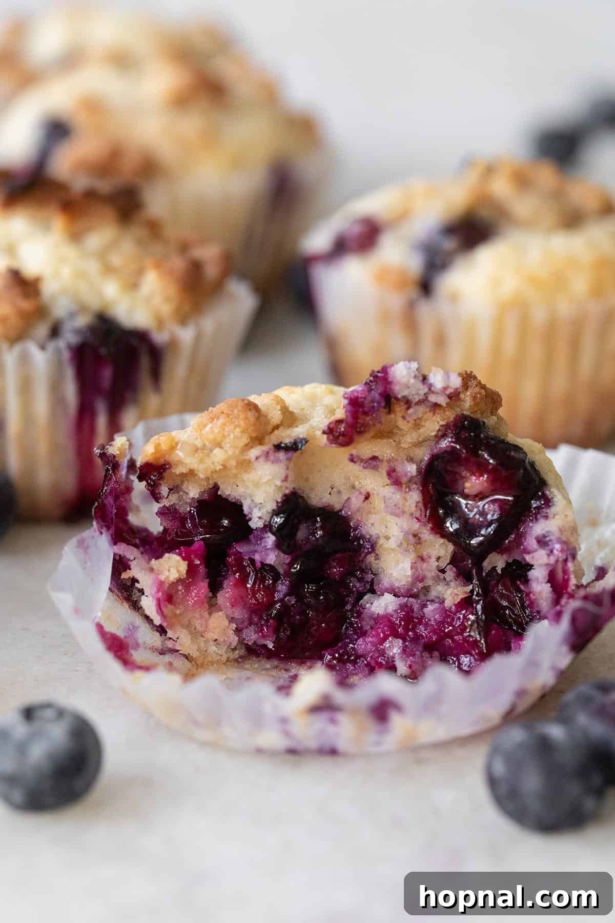 Golden Banana Blueberry Treats 7 A banana blueberry muffin with a bite taken out, revealing its soft, moist interior and abundant blueberries.