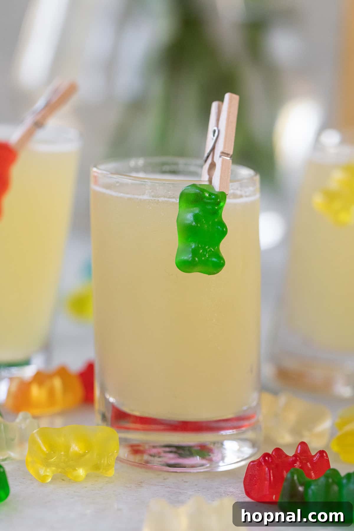 Tipsy Teddy Shot 8 A clear shot glass filled with a Gummy Bear Shot, expertly garnished with a vibrant green gummy bear clipped to its side, highlighting the playful presentation.