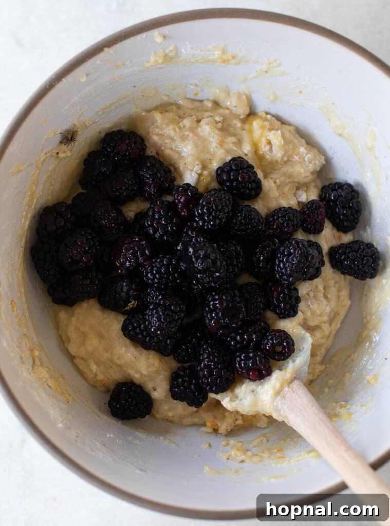 Fresh blackberries in a bowl of muffin batter.