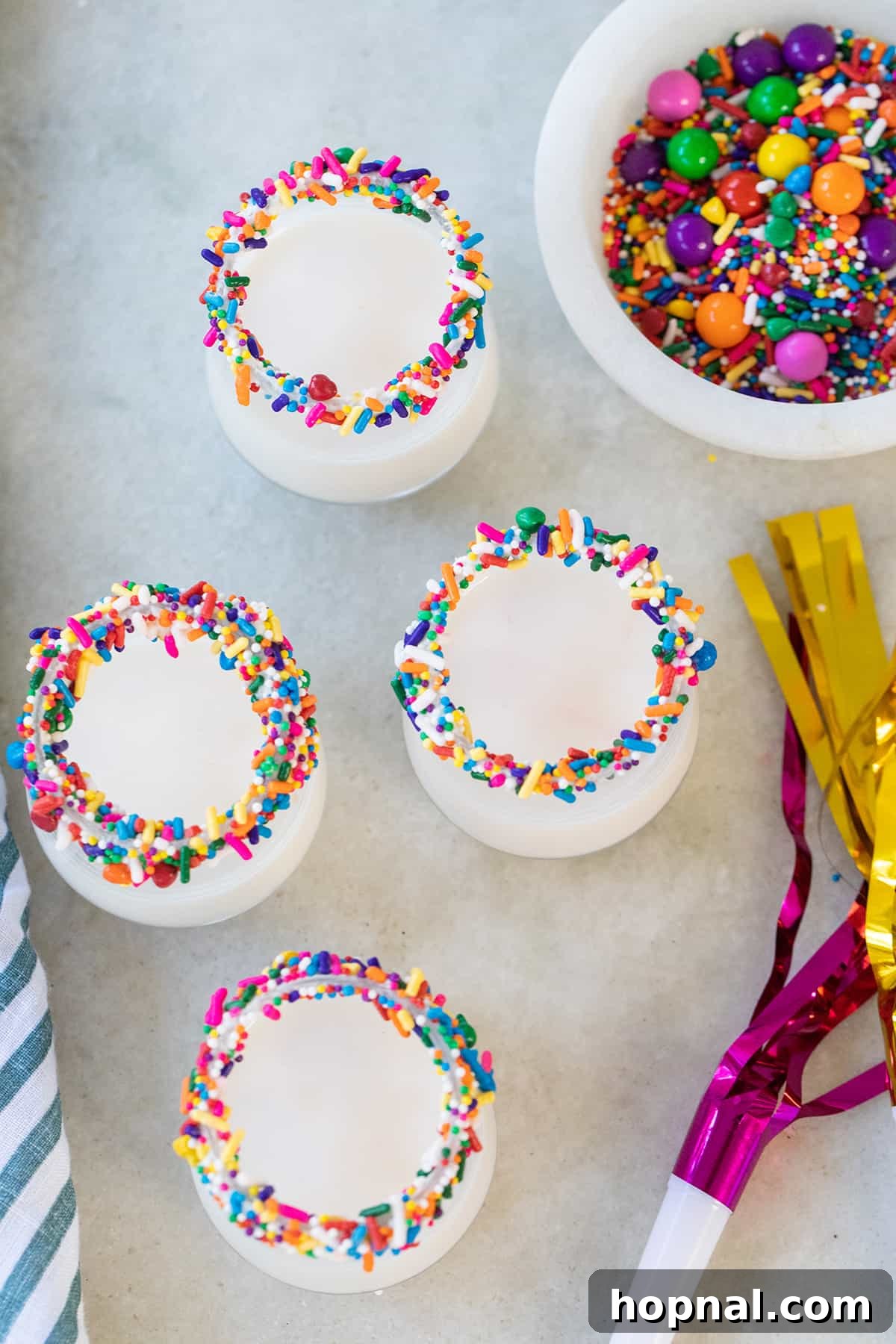 A beautifully presented birthday cake shot with whipped vodka and a vibrant colorful sprinkle rim, ready to be enjoyed.