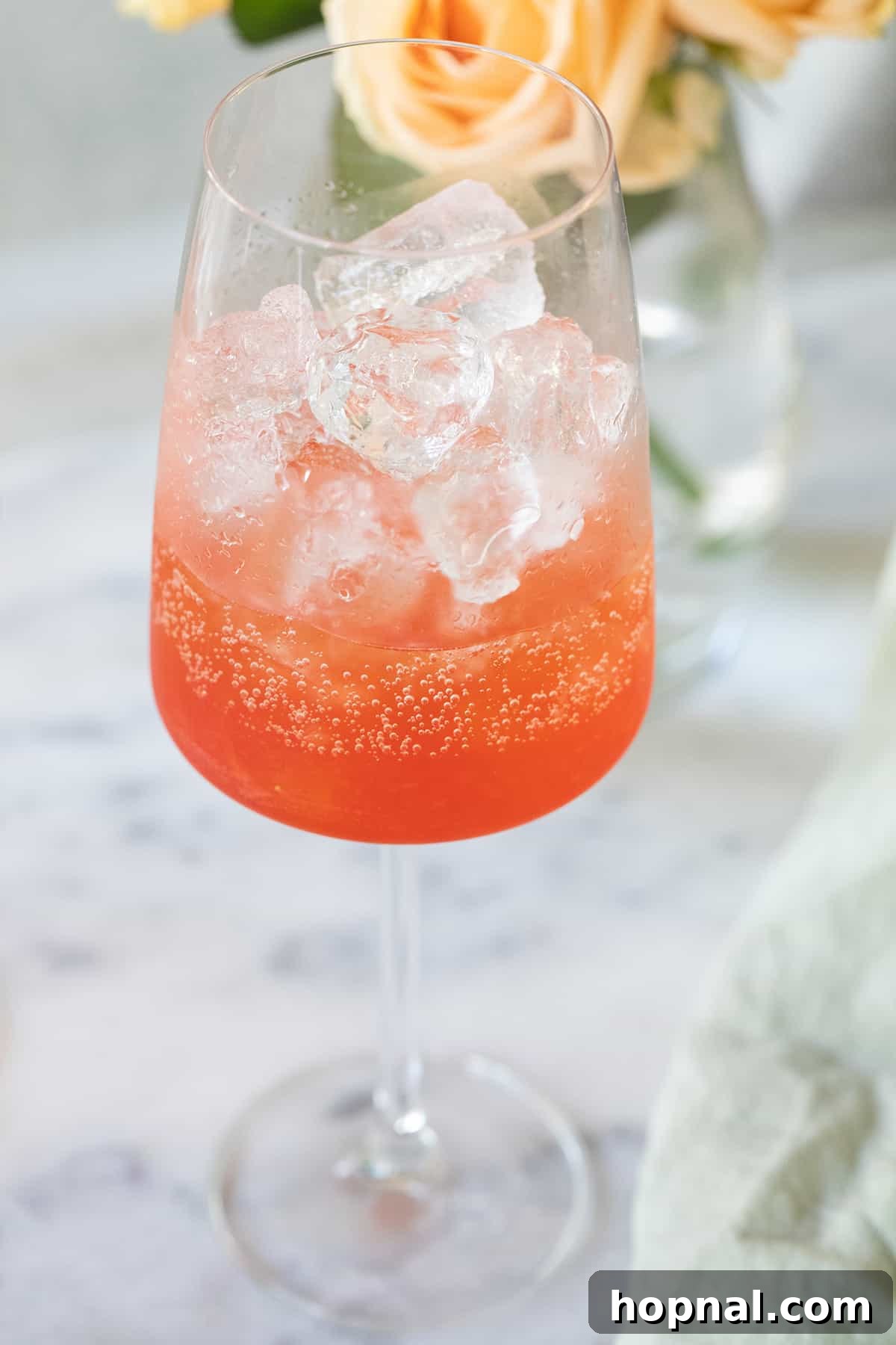 A close-up of a cocktail shaker with muddled strawberries and Aperol, demonstrating the first step in making a Strawberry Aperol Spritz.