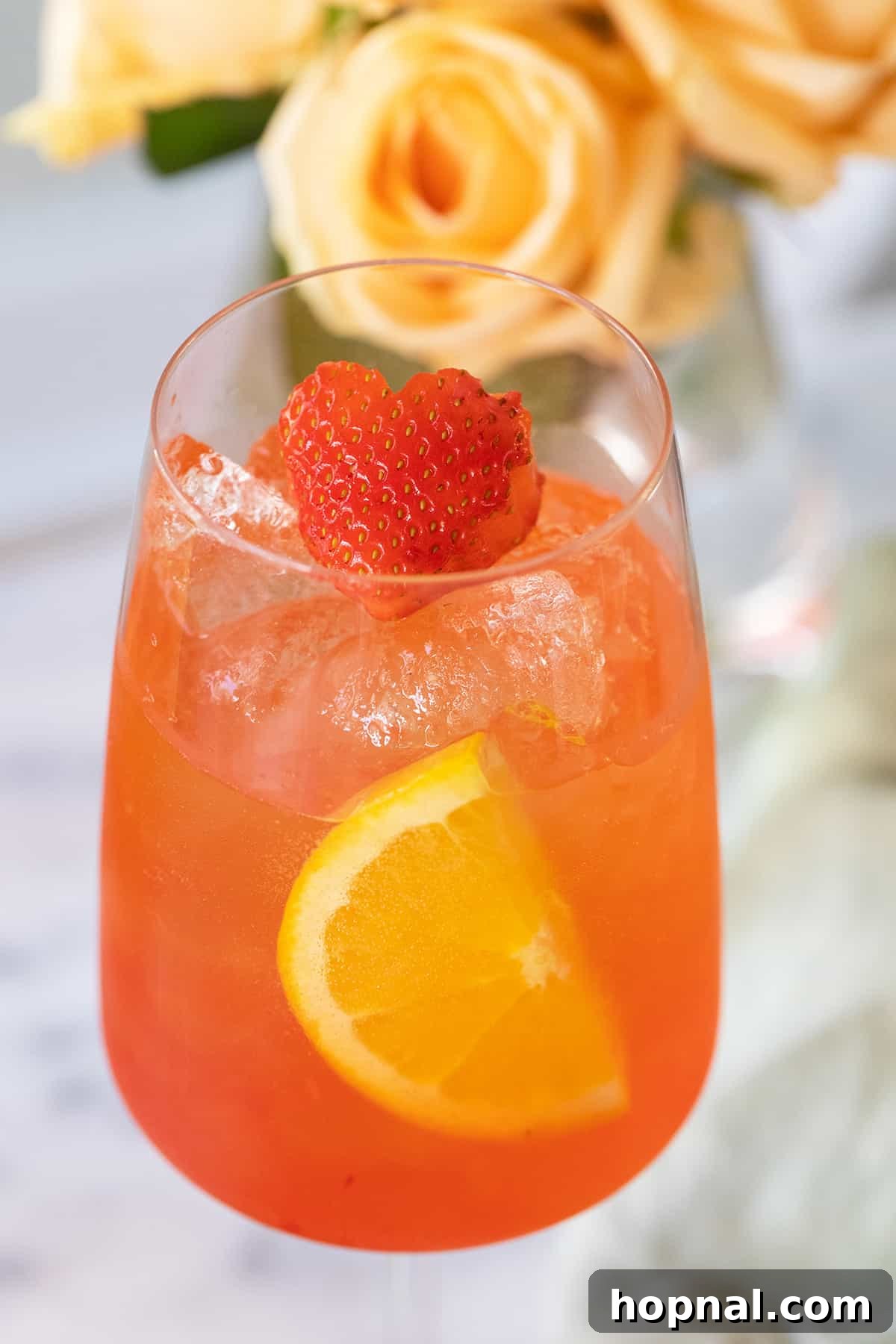 A close-up shot of a Strawberry Aperol Spritz, showing the vibrant color and strawberry garnish, inviting a refreshing sip.