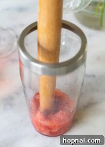 Mudding strawberries in a cocktail shaker.