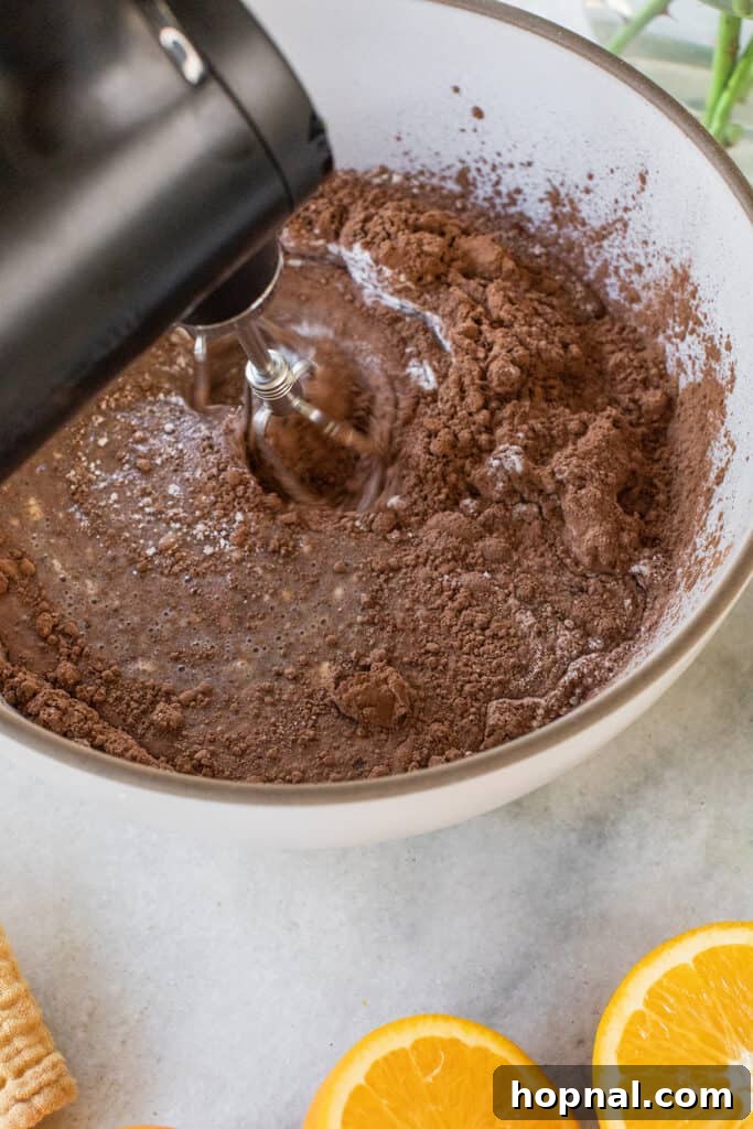 Mixing a homemade chocolate orange cake batter with an electric mixer, showing the smooth consistency.