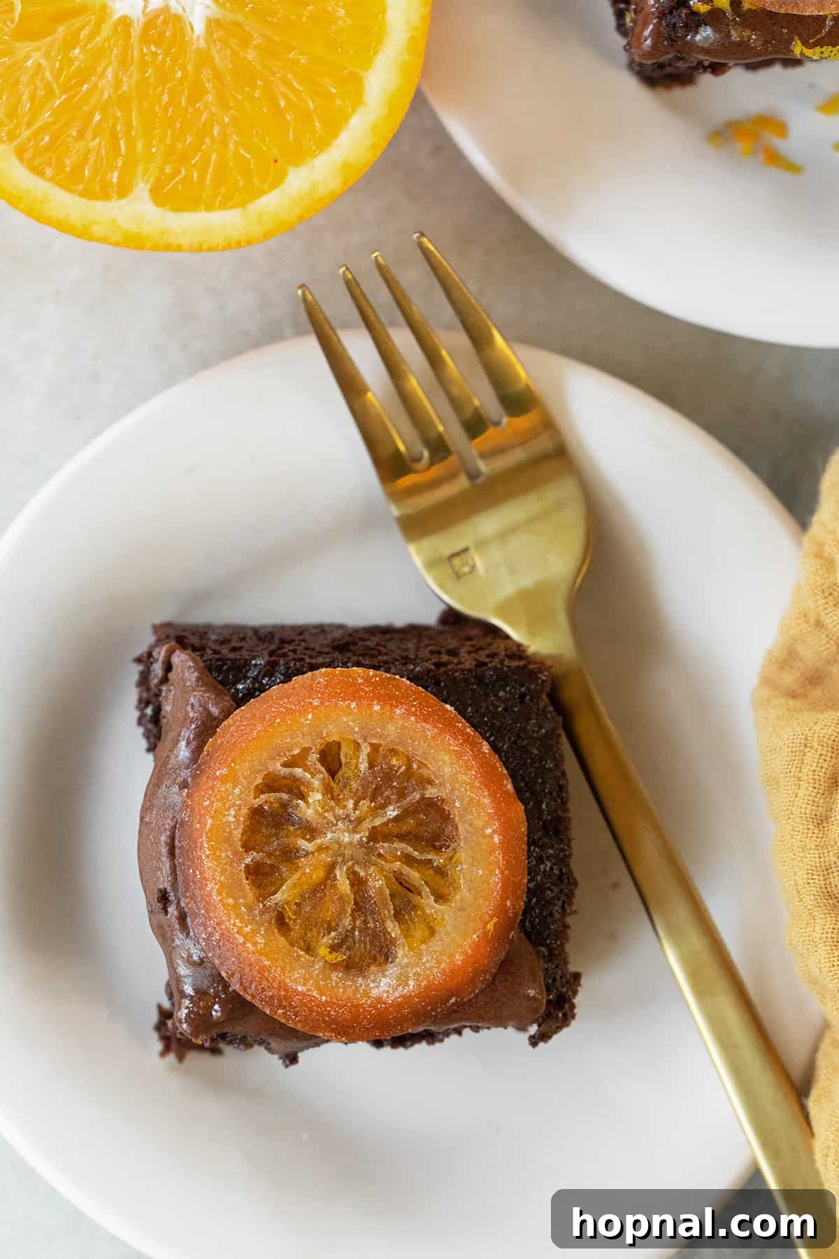 A perfectly sliced chocolate orange cake served on a dessert plate with fresh orange slices, highlighting its delectable layers and inviting appeal.