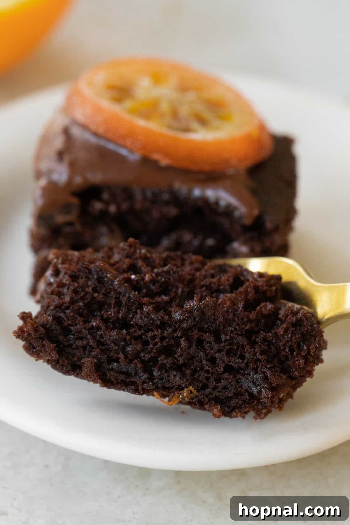 A fork breaking into a moist slice of chocolate orange cake, revealing its tender, fluffy interior.