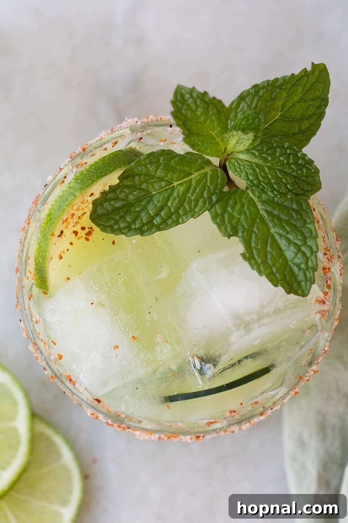 Close-up of a refreshing cucumber margarita in a salt-rimmed glass, garnished with lime and cucumber.