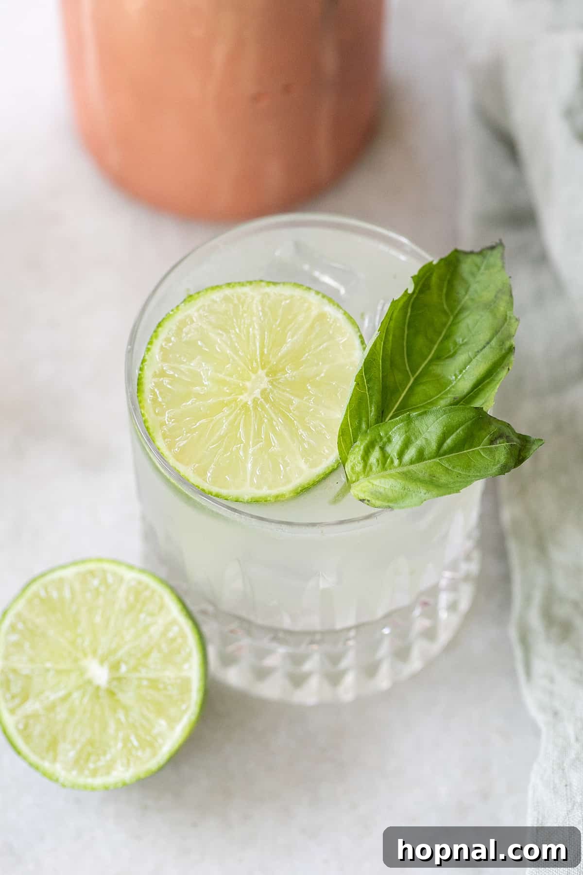 Vibrant Gin Basil Smash cocktail garnished with fresh lime and basil leaves, set against a summer backdrop.
