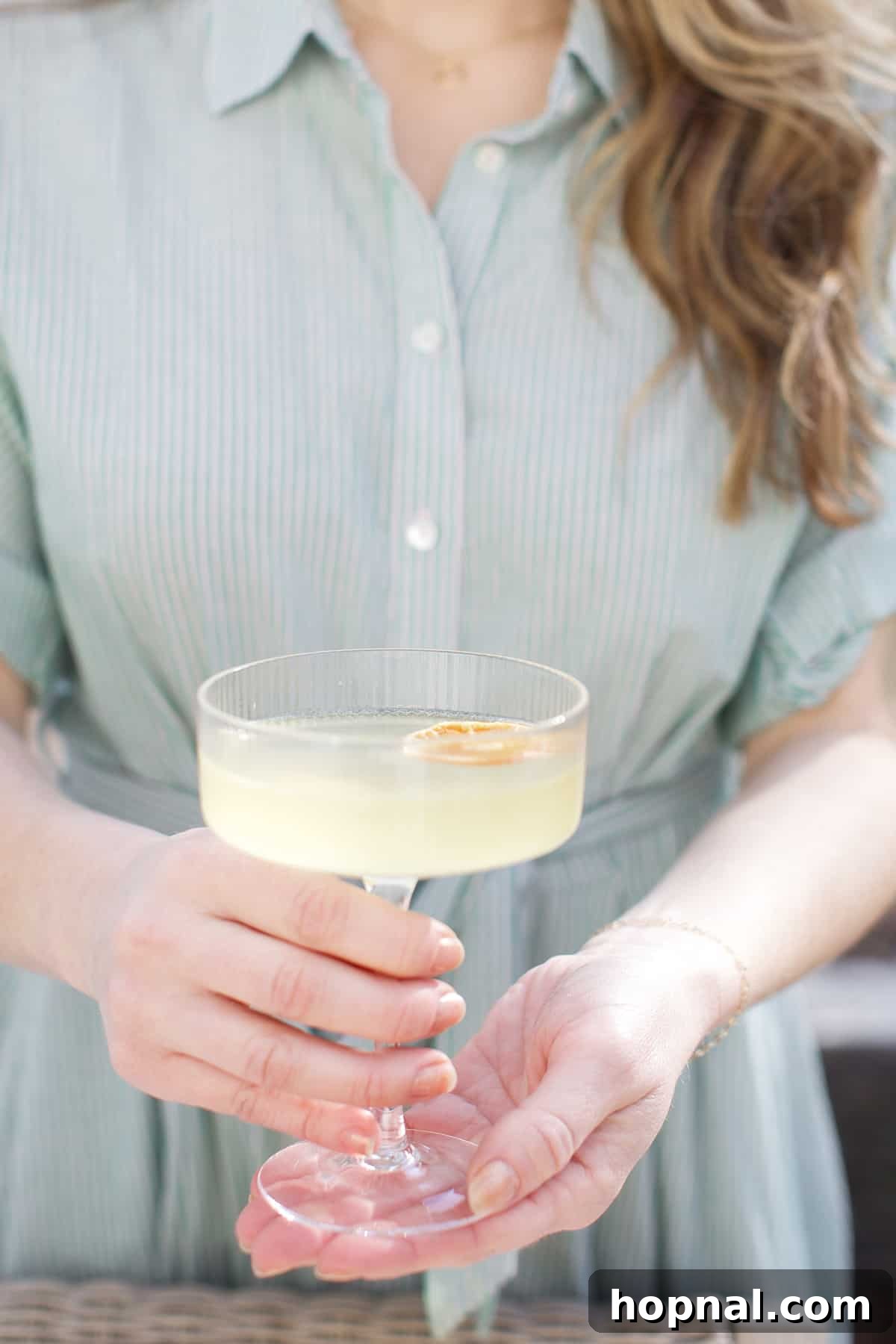 Spring Gatherings: A Lemon-Kissed Table 10 Eden Passante gracefully holding a refreshing lemon spritz cocktail, embodying the spirit of a vibrant spring gathering.