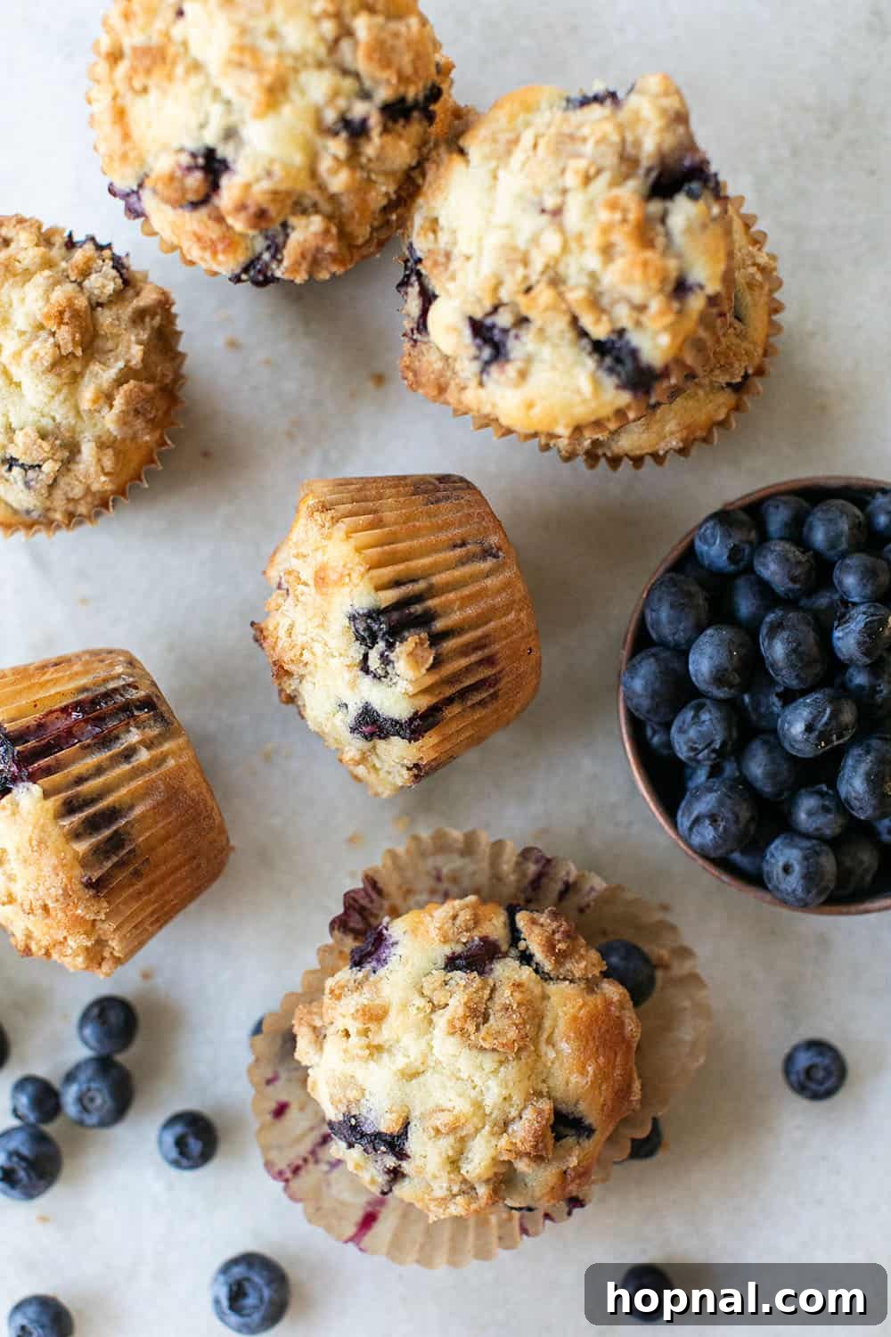 A close-up of a freshly baked blueberry muffin with a golden streusel topping, showcasing its tender crumb and plump, juicy blueberries.