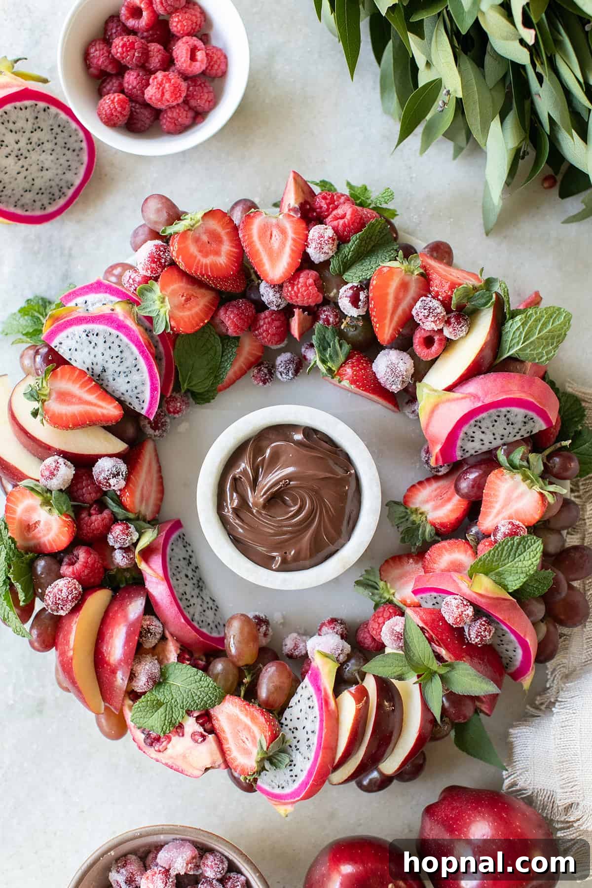 Elegant Christmas Fruit Platter with Red Fruits Christmas wreath fruit platter with an array of red fruits and a rich chocolate dipping sauce.