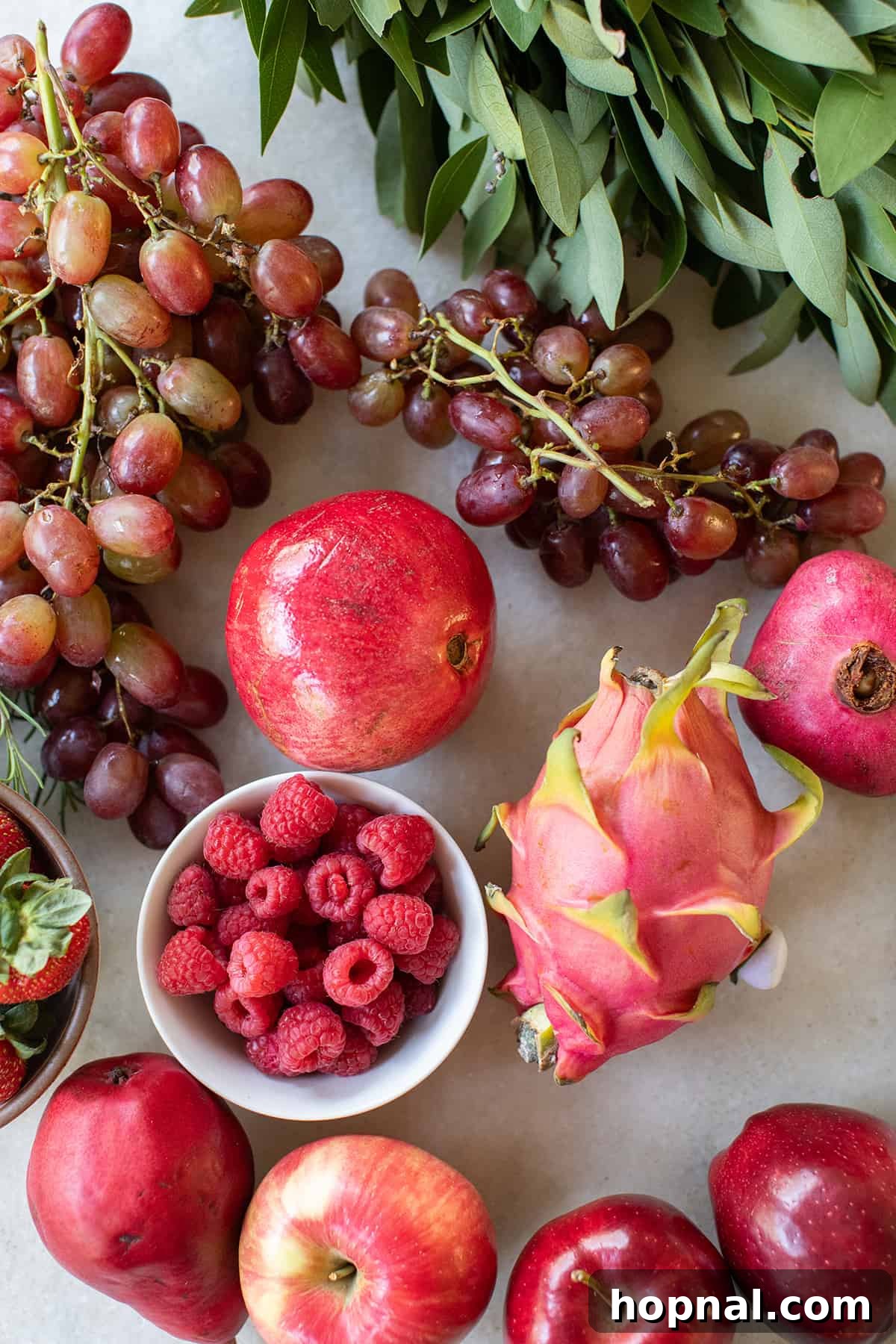Assortment of Red Fruits for a Holiday Platter An assortment of fresh red fruits including grapes, pomegranates, raspberries, dragonfruit, and strawberries, ready for a festive fruit platter.