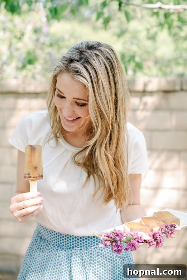 Mom's Garden Tea Oasis 8 Host, Eden Passante, holding two refreshing Lilac Earl Grey Popsicles for guests