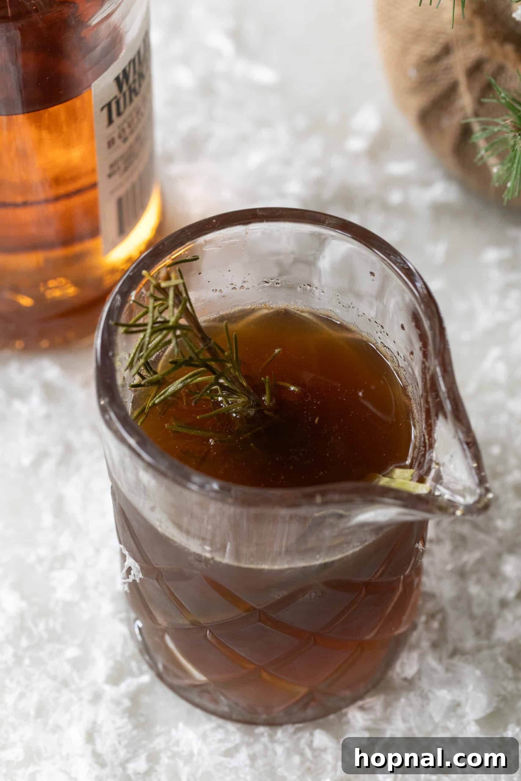 Homemade honey simple syrup with rosemary sprigs infusing in a saucepan.