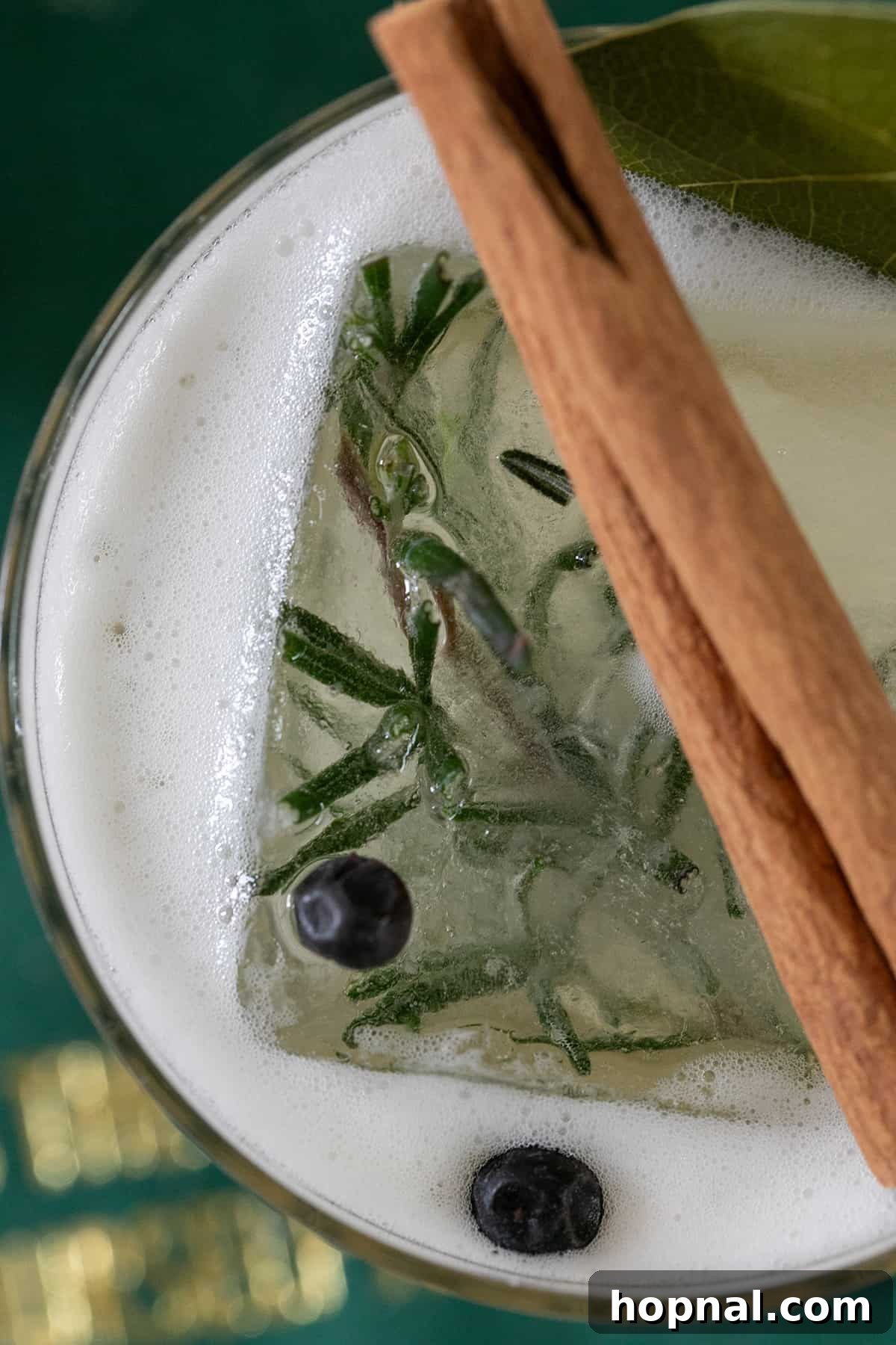 Custom ice cube with rosemary and juniper berries in a glass.