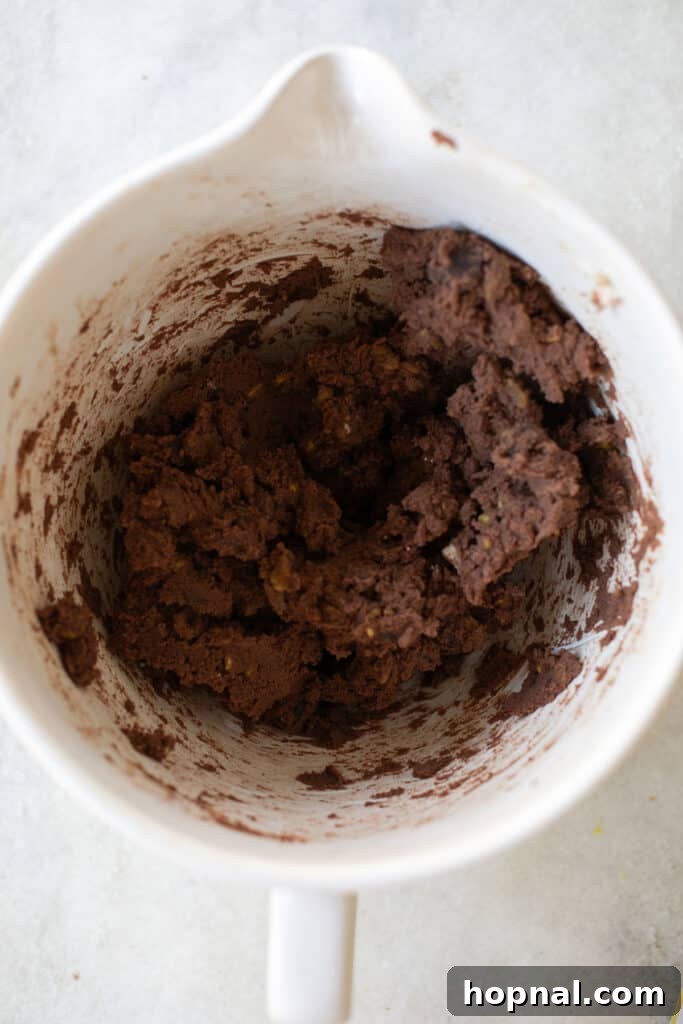 Rich chocolate sable cookie dough being mixed in a large bowl, showcasing its smooth, consistent texture.