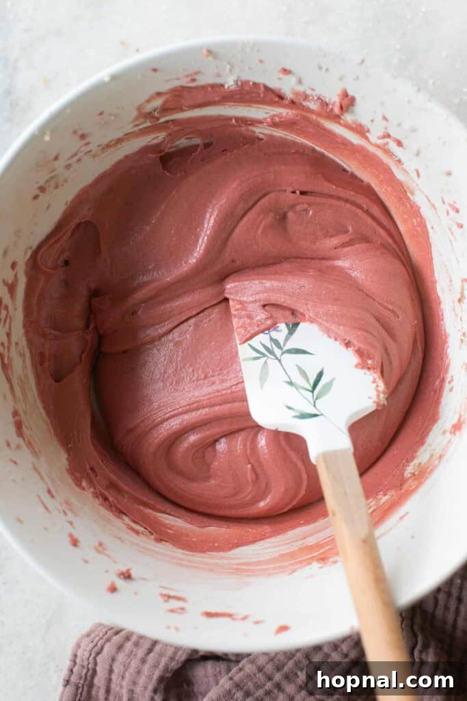 Vibrantly red red velvet donut batter, ready to be piped into a donut pan.