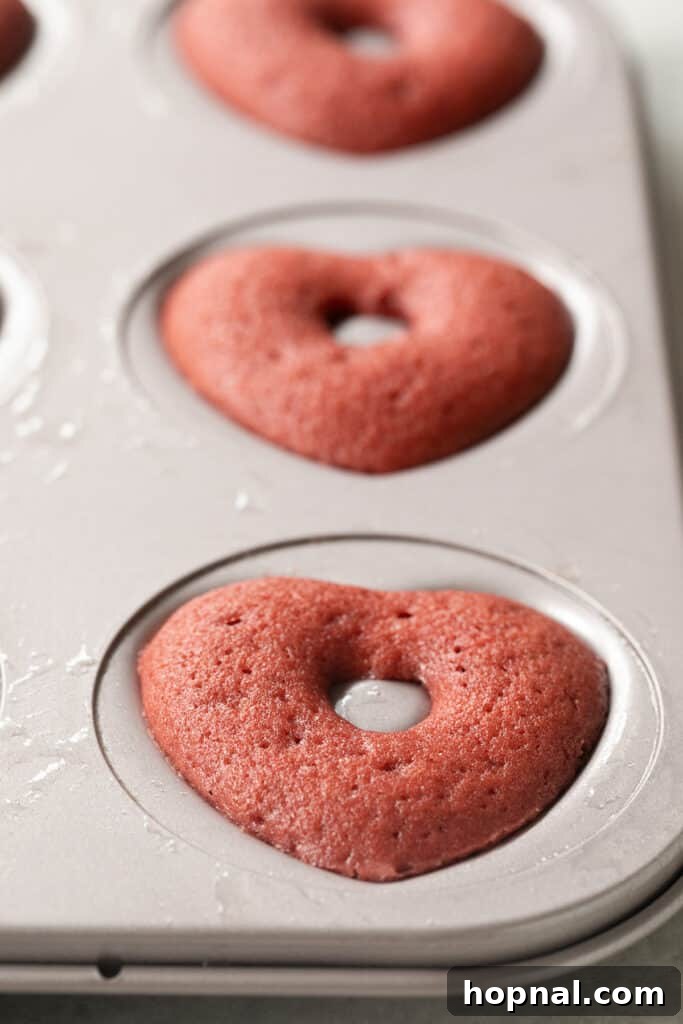 A tray of perfectly golden-brown baked red velvet donuts, fresh out of the oven.
