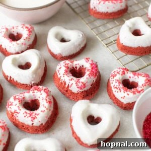 Heart-shaped red velvet donuts with sprinkles and a rich cream cheese glaze.