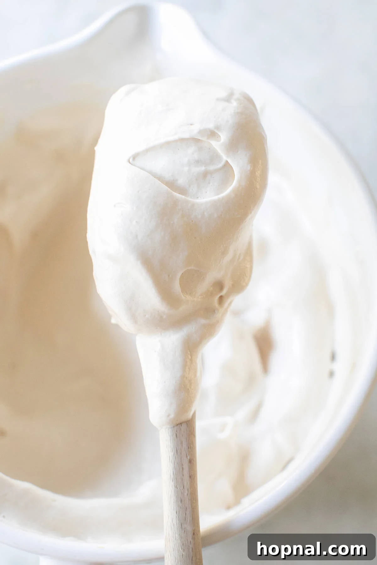 A large spatula generously coated with thick, fluffy maple syrup frosting, ready to be spread.