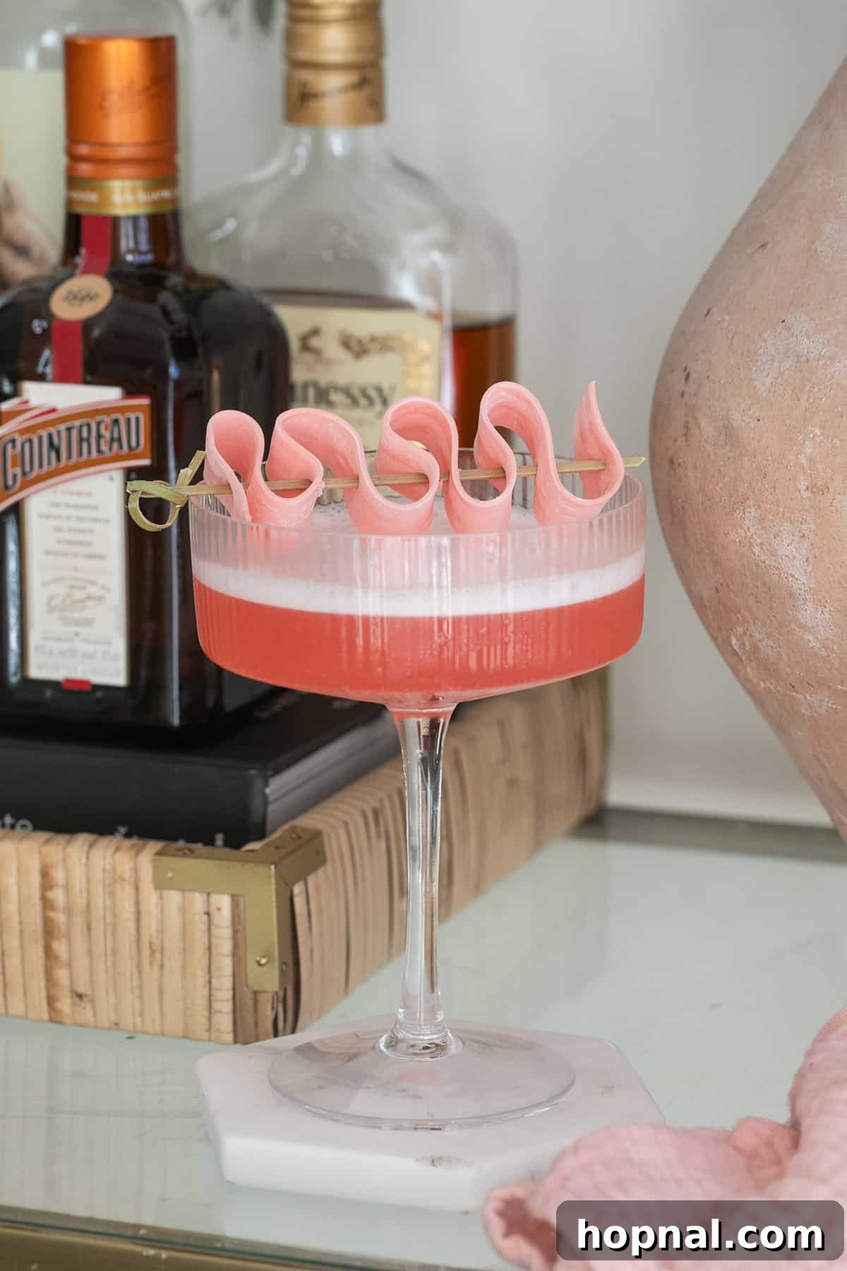 Bubblegum Bliss Vodka 4 A vibrant pink bubble gum cocktail made with infused vodka, garnished with pink bubble gum, on a stylish bar cart.