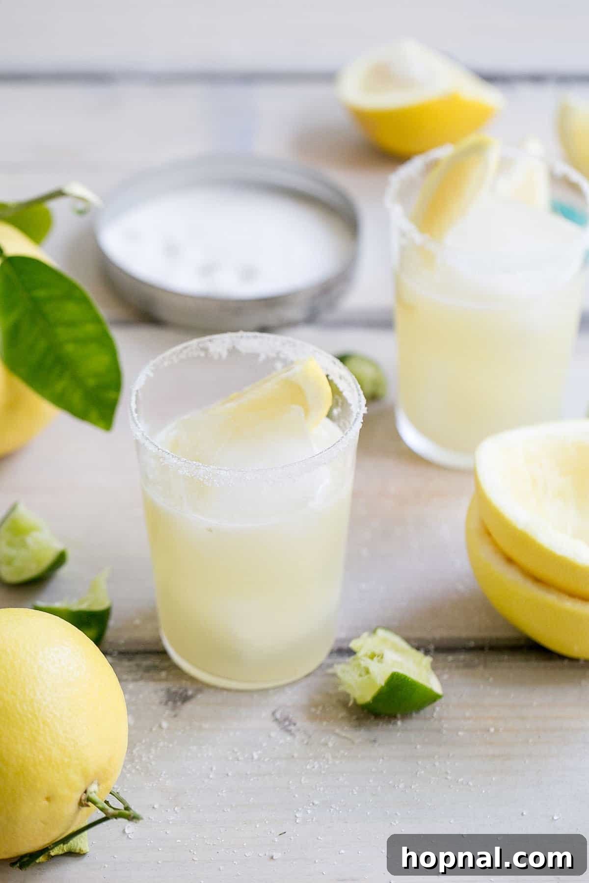 Two grapefruit margaritas with garnishes on a table