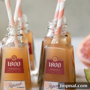 Mini Paloma shots in tiny tequila bottles with straws.