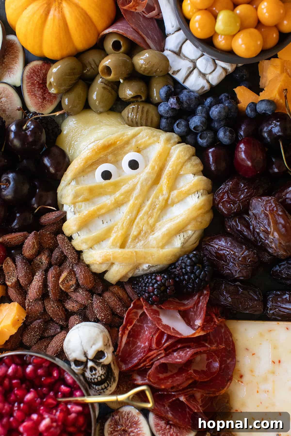 Mummy brie recipe displayed on a Halloween themed cheese platter.