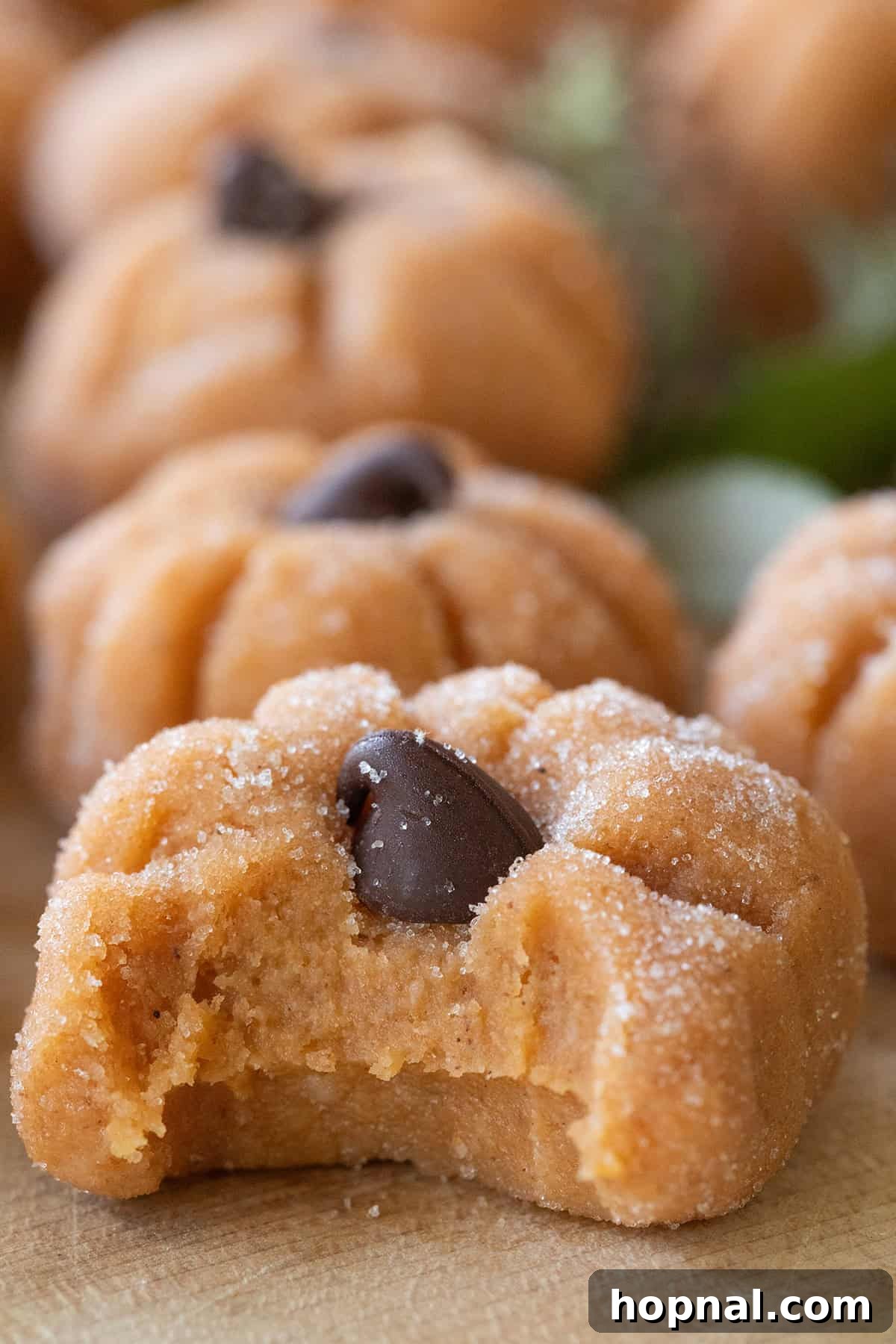 A bite taken out of a pumpkin cheesecake truffle shaped as a pumpkin. Reveals the creamy, spiced interior.
