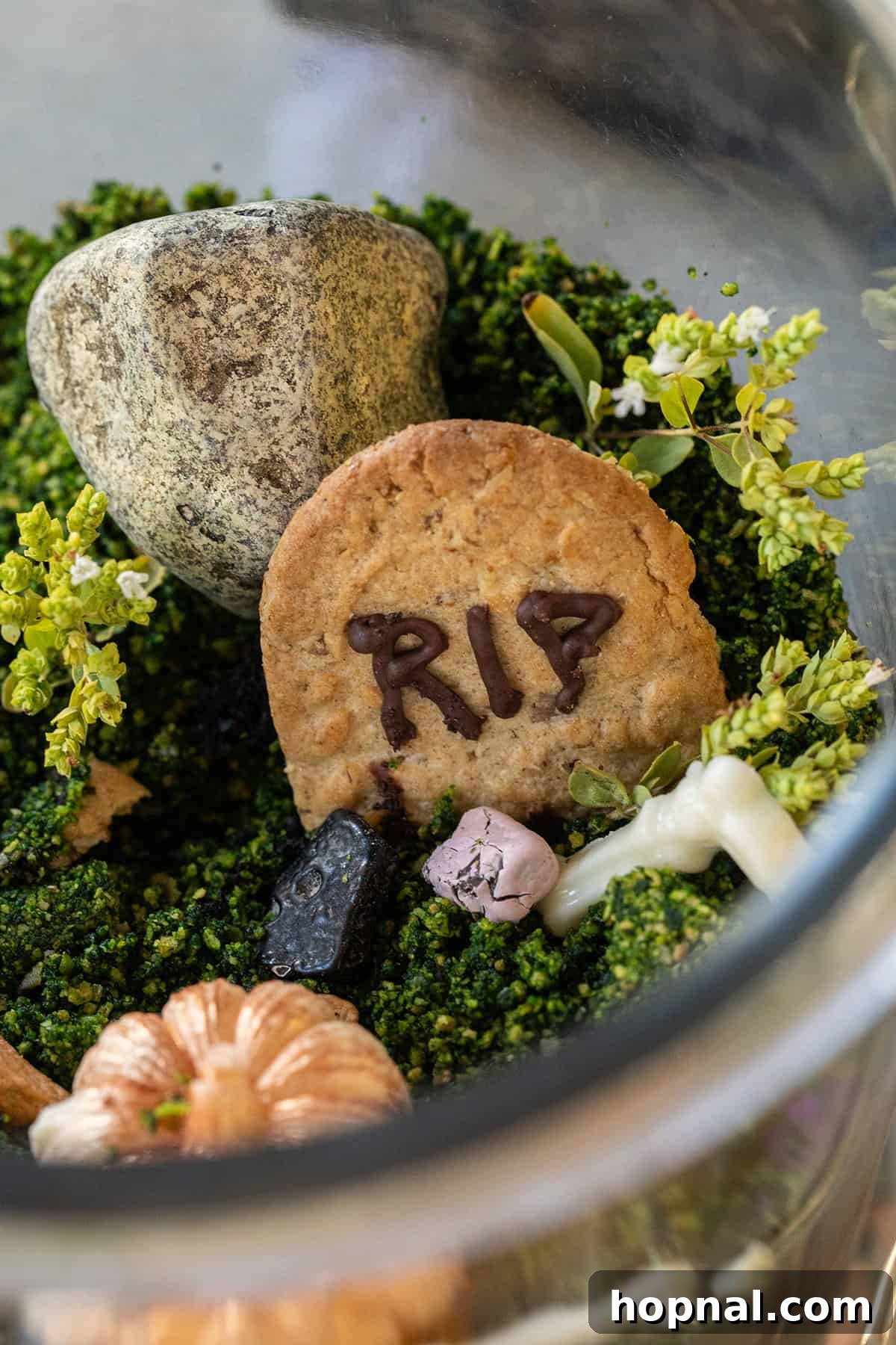 Halloween dessert designed as a cemetery scene in an edible terrarium.