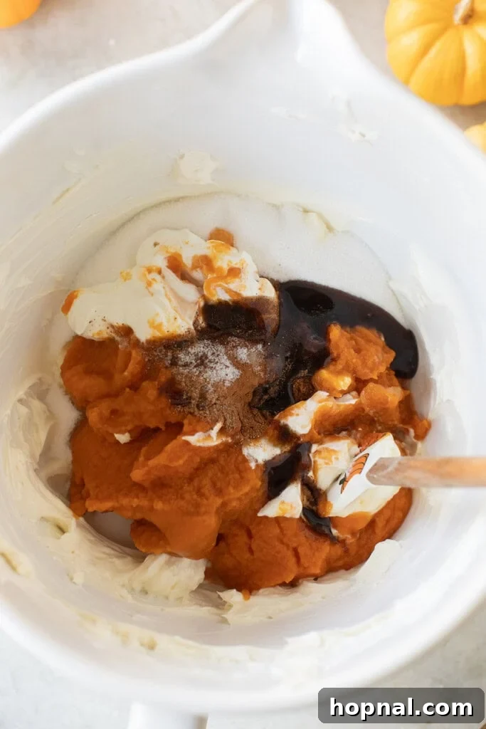 The smooth, orange-hued pumpkin cheesecake filling being mixed in a large bowl, showcasing its creamy texture.