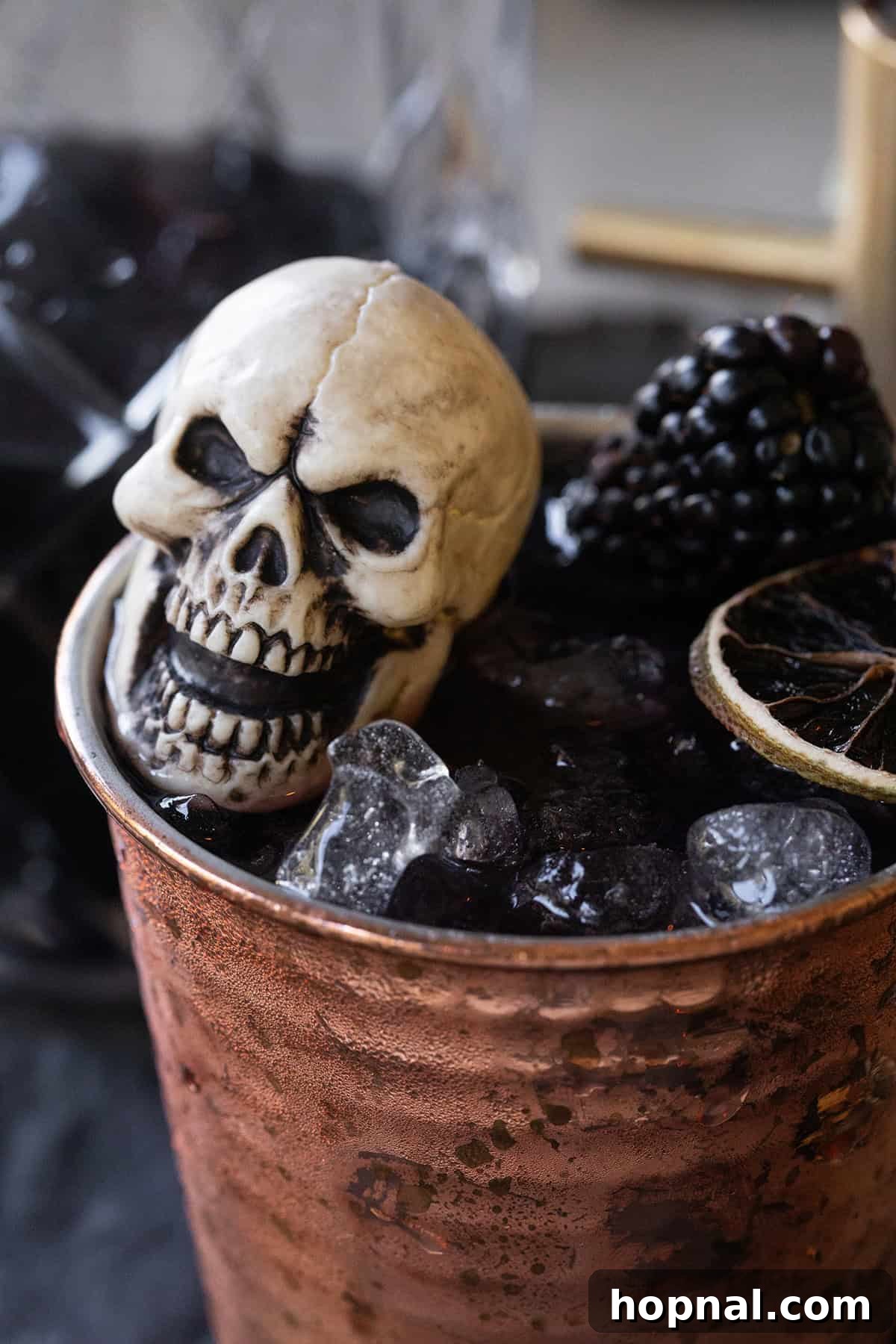 Halloween Moscow Mule with blackberries, ginger, and black vodka served in a copper cup, ready for a spooky party.