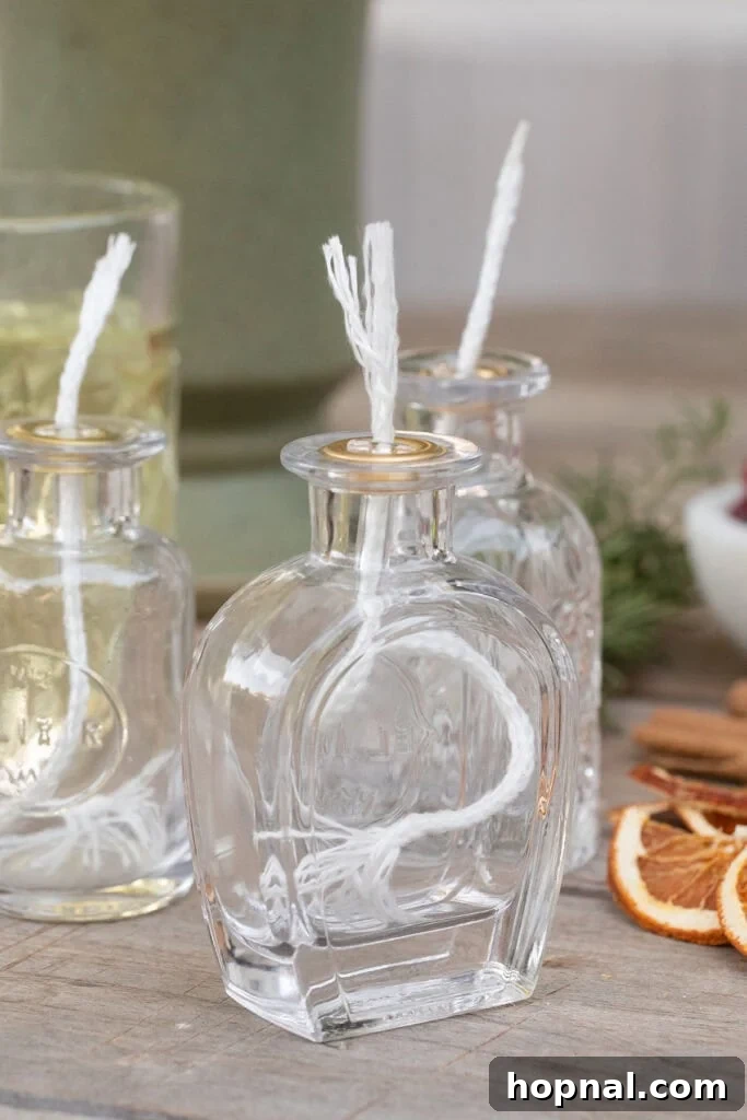A collection of small glass jars with wicks and a larger jar filled with oil, ready for making homemade oil candles.