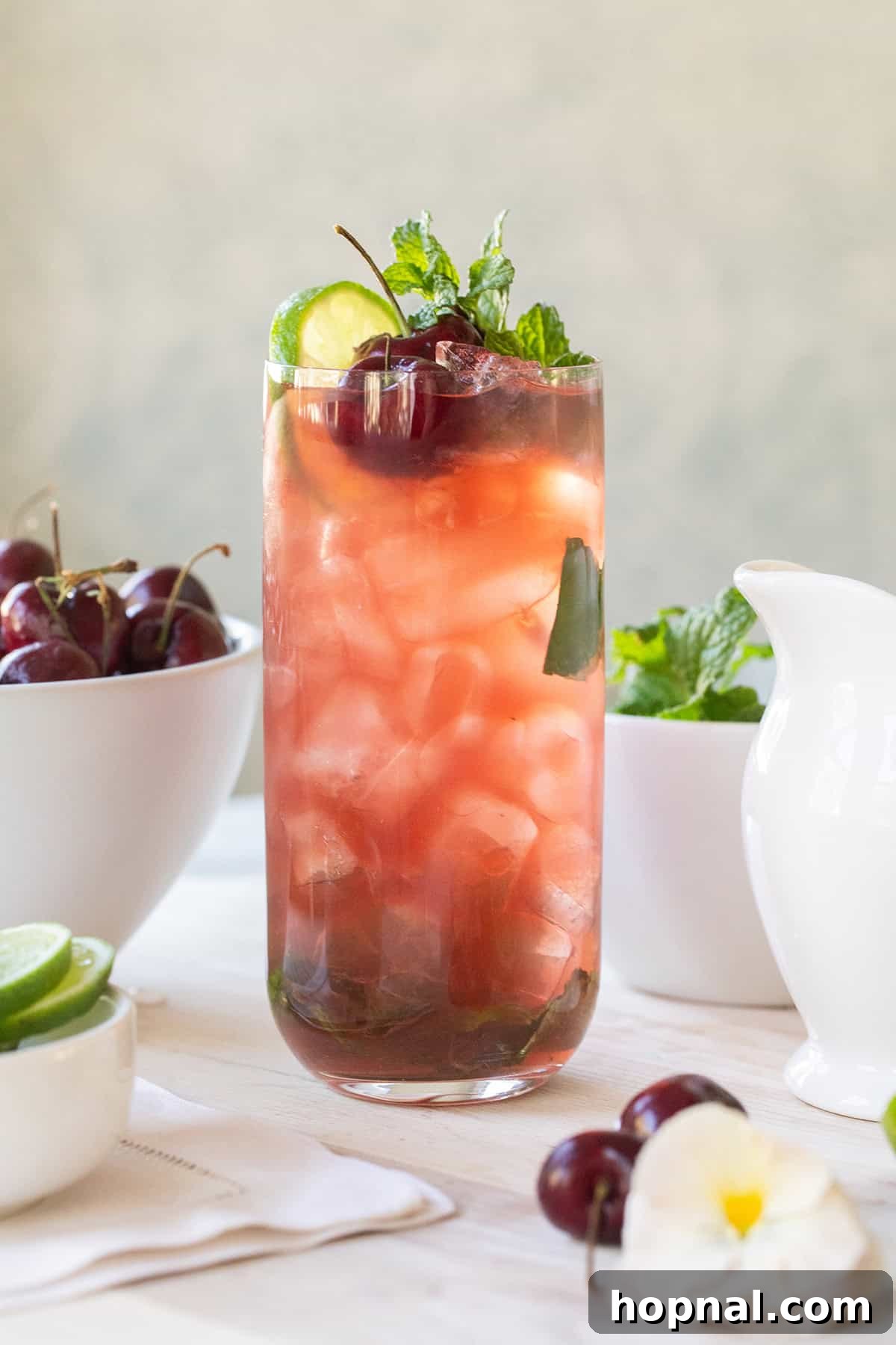 Cherry mojito in a tall glass with crushed ice, cherry juice, fresh mint and a lime wheel, beautifully composed for enjoyment.