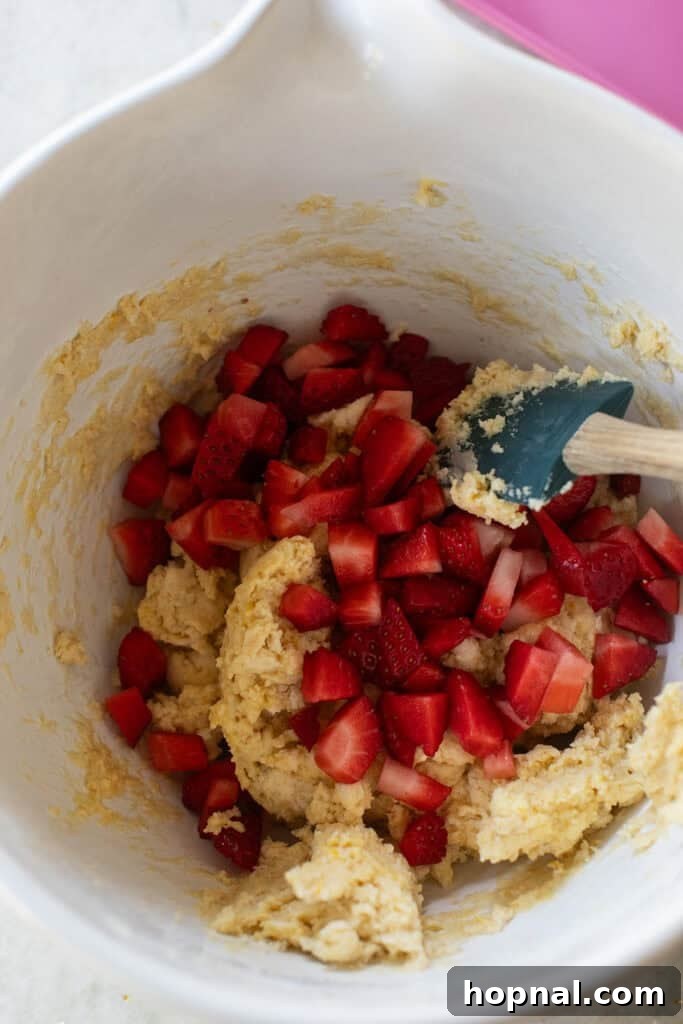 Chopped fresh strawberries gently folded into scone dough, showing the fruit evenly distributed before shaping.