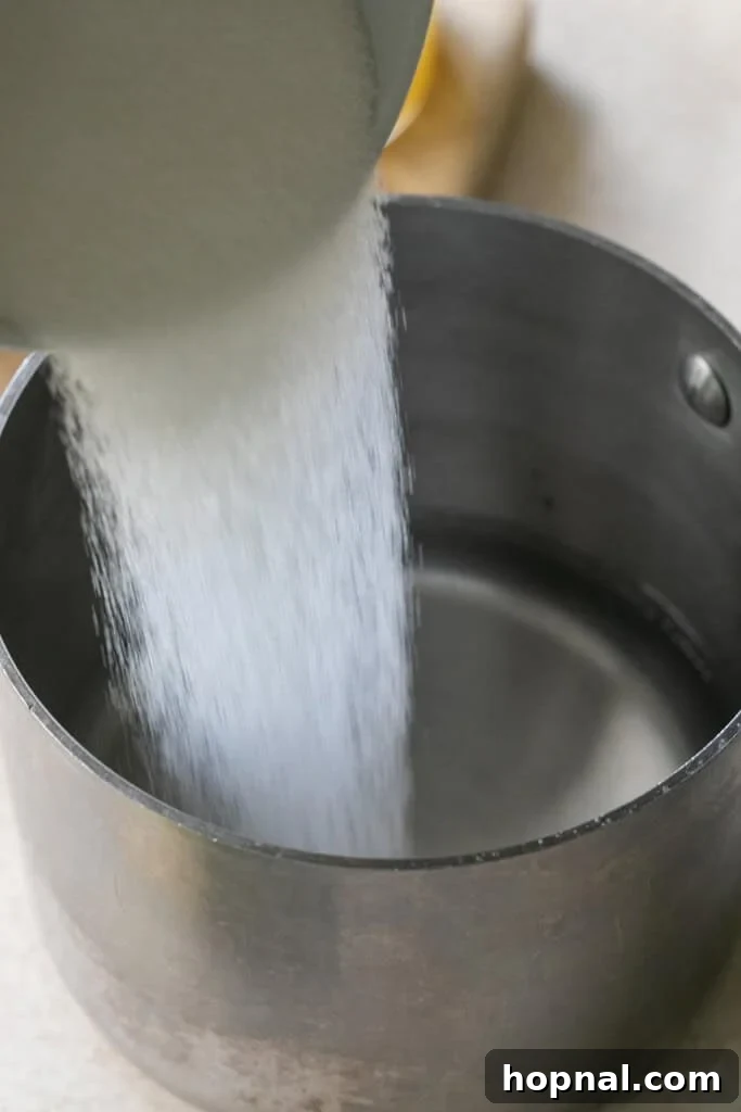 Pouring granulated sugar into a saucepan with water, beginning the lavender syrup preparation.