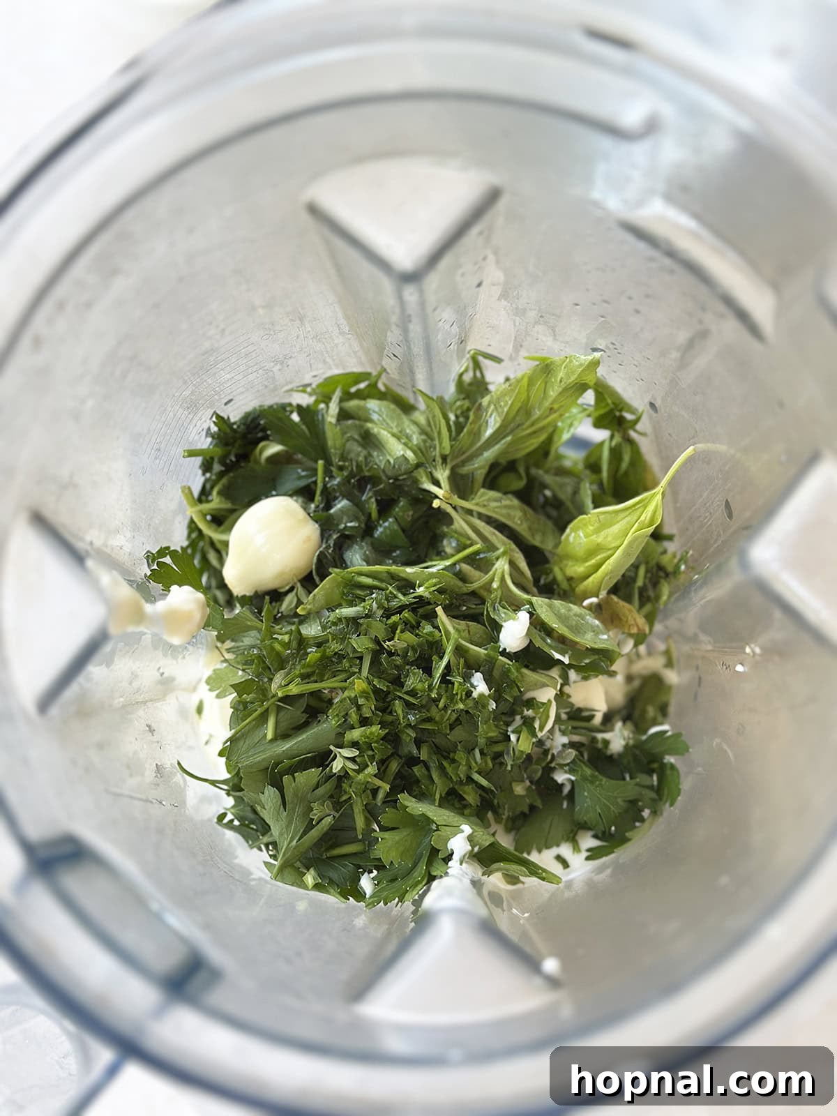 All the green goddess dip ingredients, including fresh herbs, yogurt, and mayonnaise, placed in a blender carafe, ready for blending.