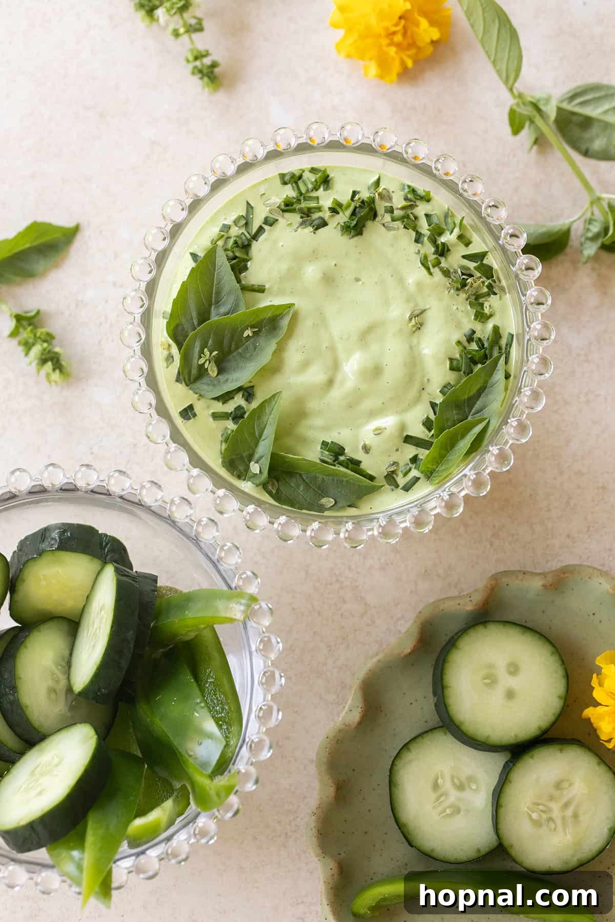 Close-up of a bowl of creamy green goddess dip, garnished with fresh herbs and cracked black pepper, ready for serving.