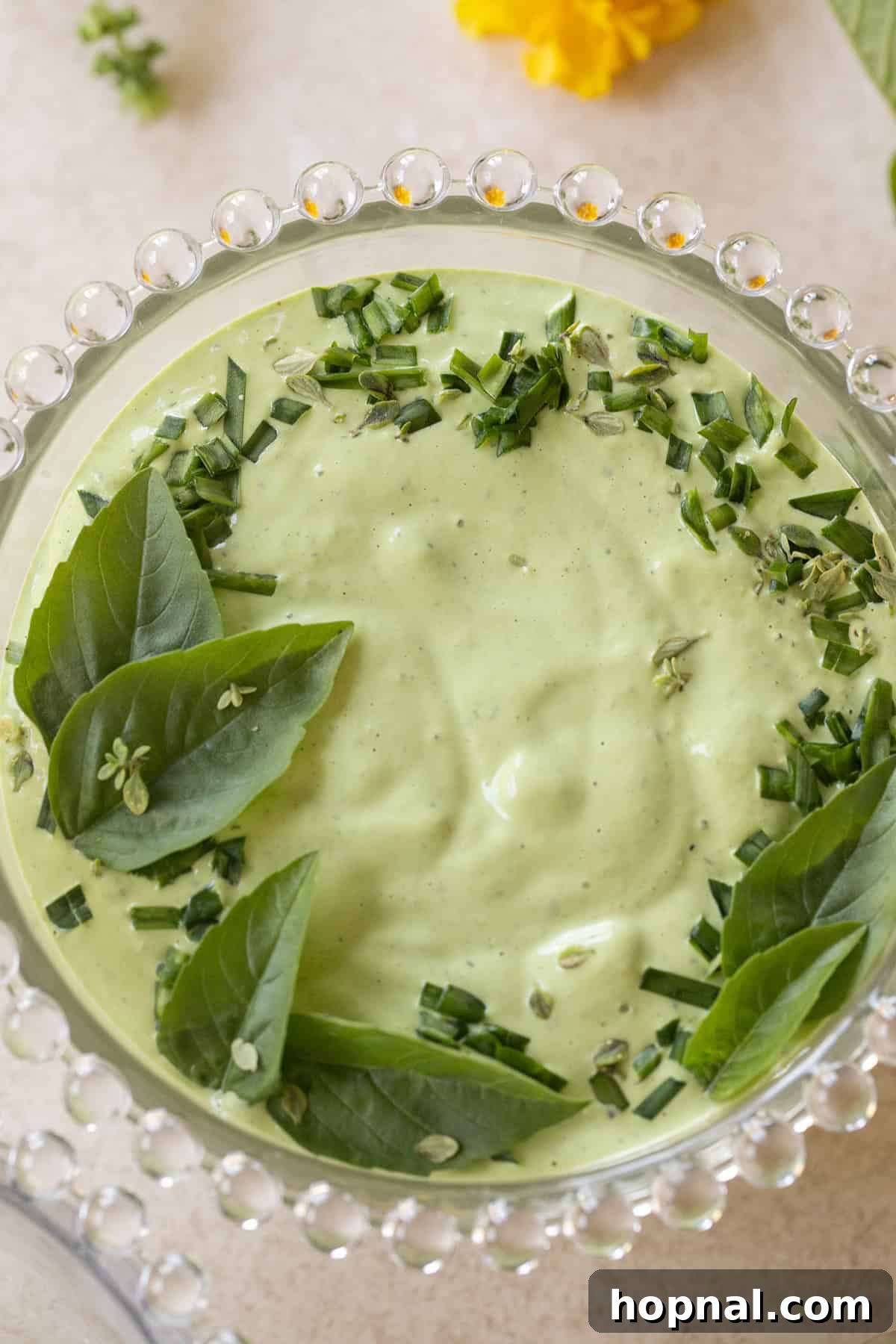 A bowl of vibrant green goddess dip, garnished with fresh herbs, suitable for dipping or as a salad dressing base.