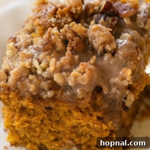 Close-up of a slice of pumpkin coffee cake with glaze and streusel.