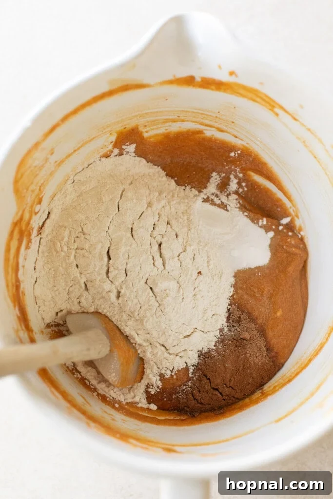 Warm Spiced Pumpkin Crumb Cake 5 Dry ingredients for the pumpkin coffee cake, including flour and spices, being gently added to the wet mixture in a stand mixer.