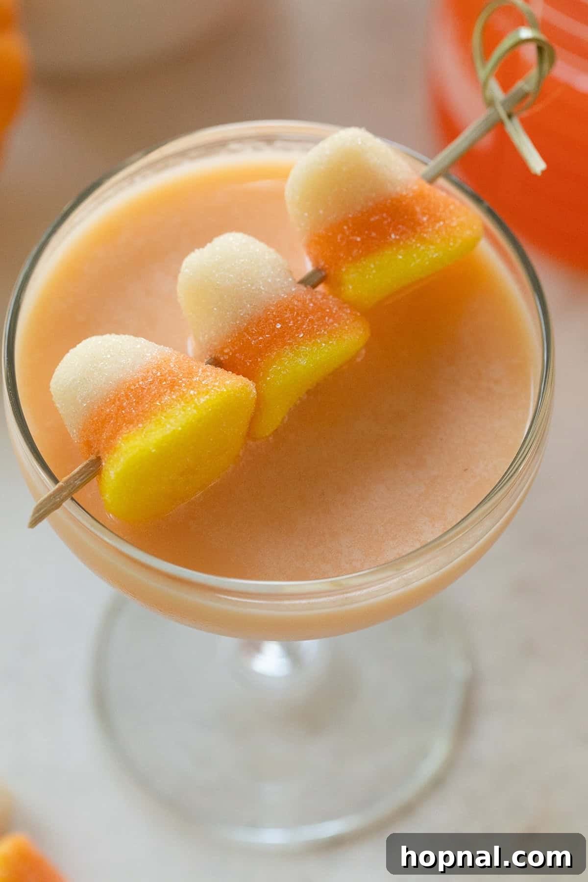Candy corn martini with gummy candy corn garnishes, elegantly served in a coupe glass.