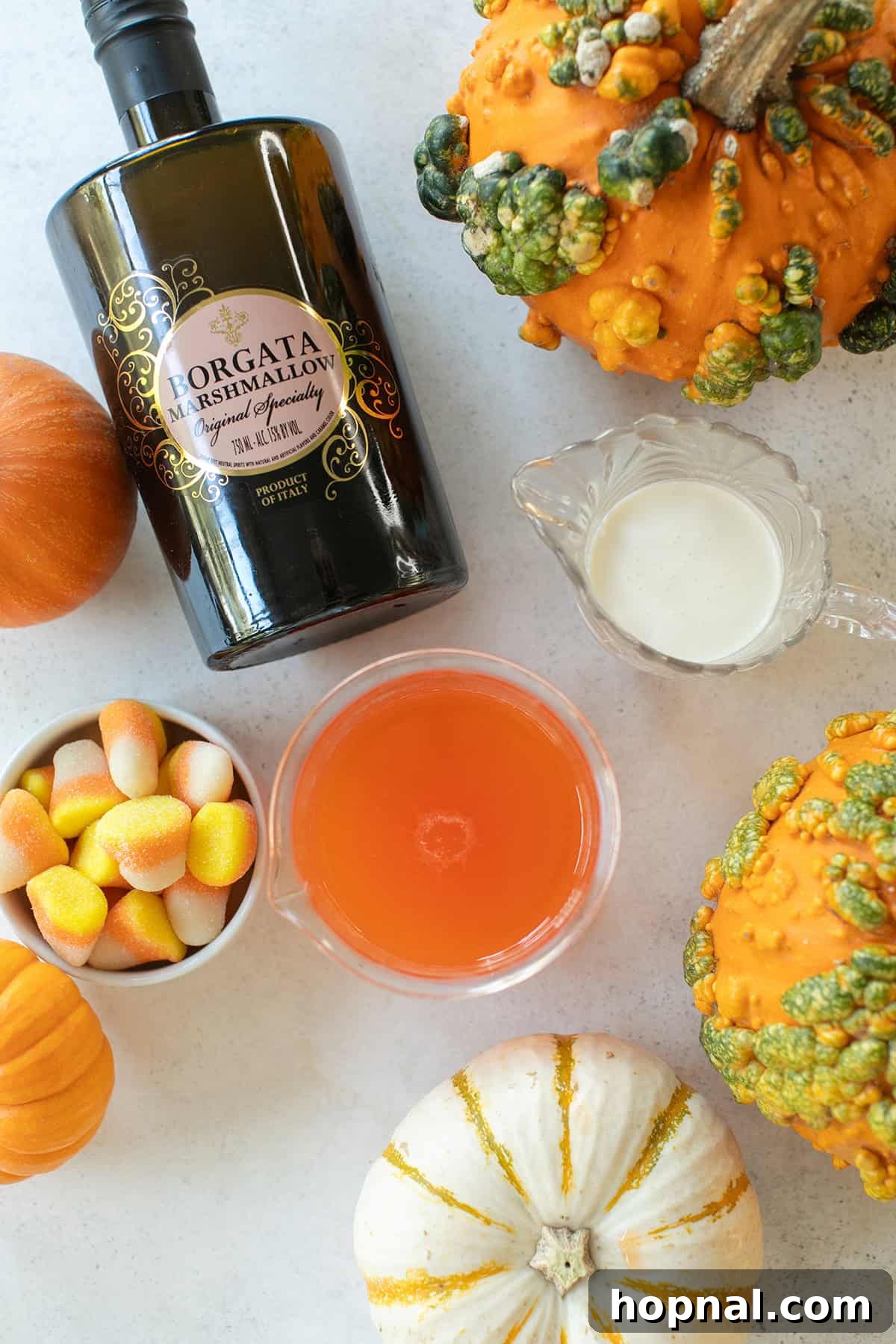 Essential ingredients for crafting a Candy Corn Martini: candy corn infused vodka, marshmallow liqueur, and cream.