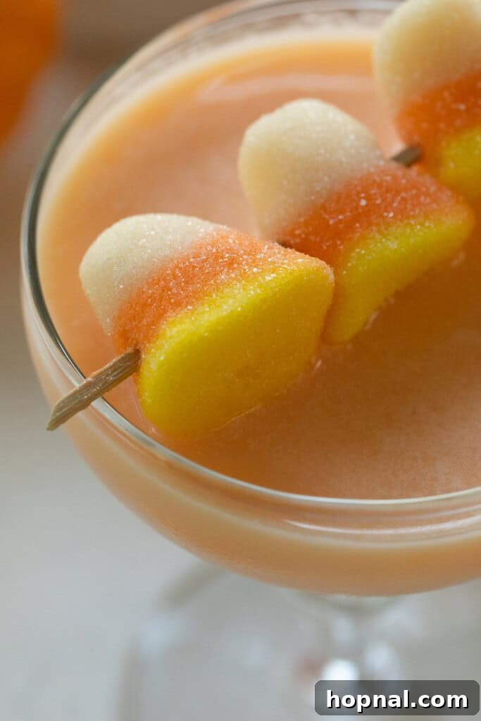 A close-up of a Candy Corn Martini garnished with gummy candy corns.