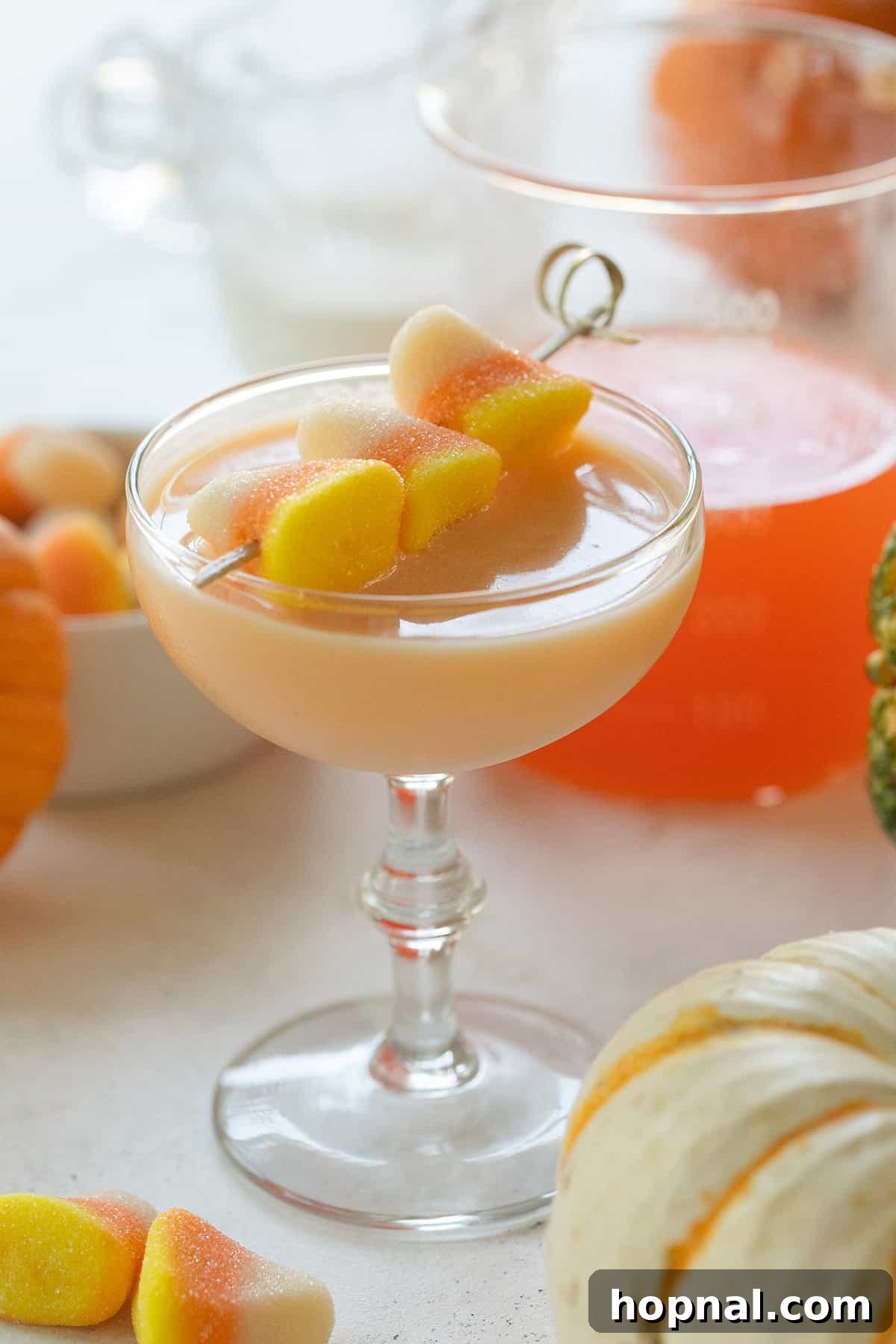 A stunning Candy Corn Martini cocktail in a elegant glass, showcasing its vibrant orange hue and playful candy corn garnish.