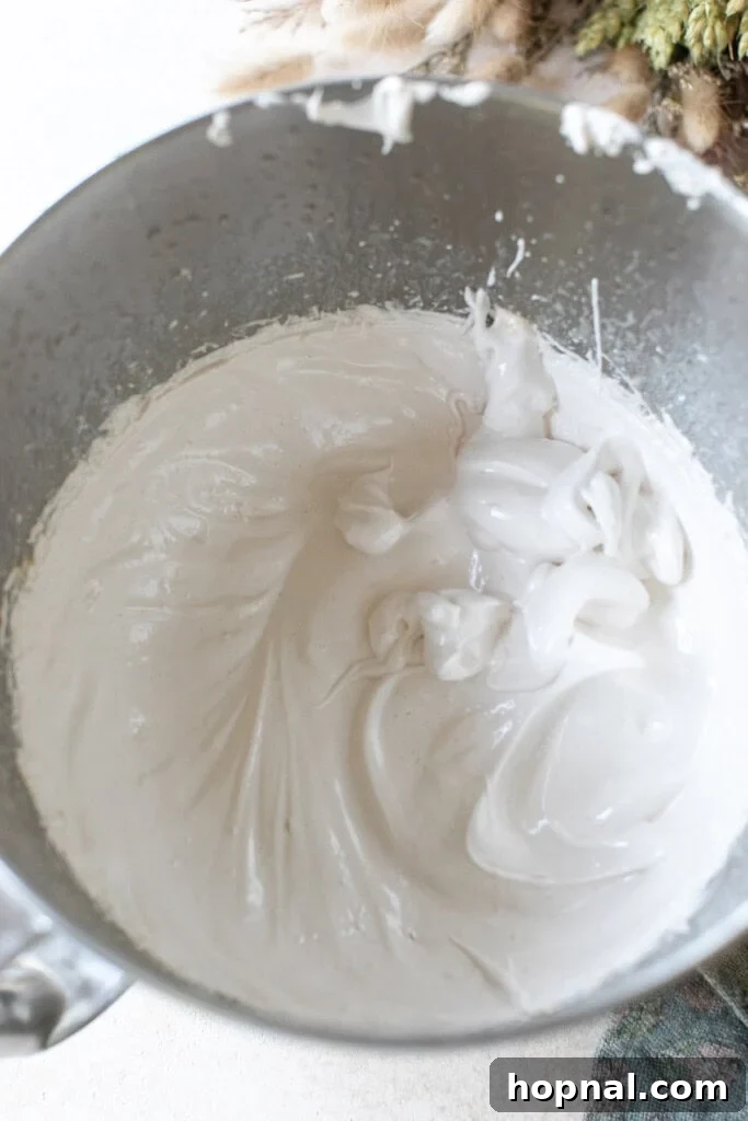 Pillowy Maple Dreams 5 Whipped maple syrup marshmallow fluff to make marshmallows, showing its thick, glossy texture in a stand mixer.