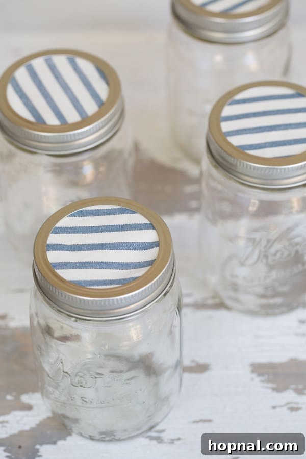 Party Perfect Festive Jar Decor 3 Close-up shot of a single Ball canning jar with a vibrant blue patterned fabric cover, secured with a metal lid ring, showcasing handmade charm.